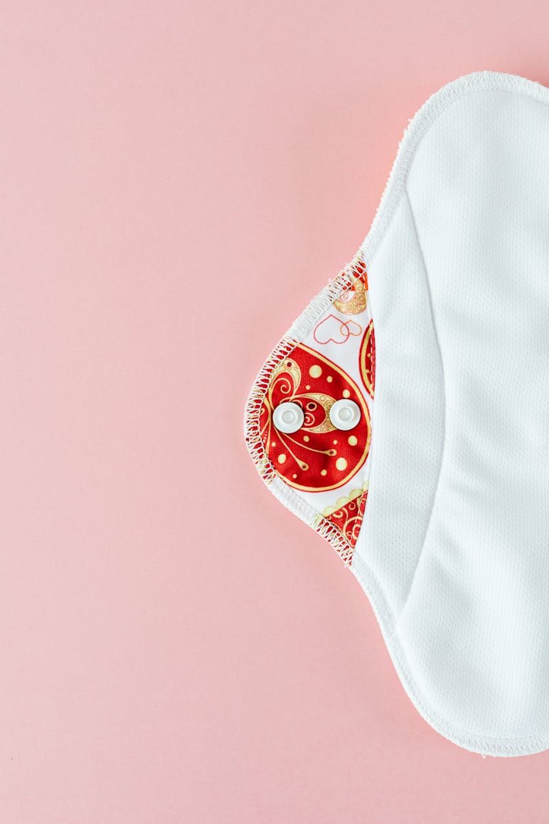 Eco-friendly reusable menstrual pad on soft pink background promoting zero waste.